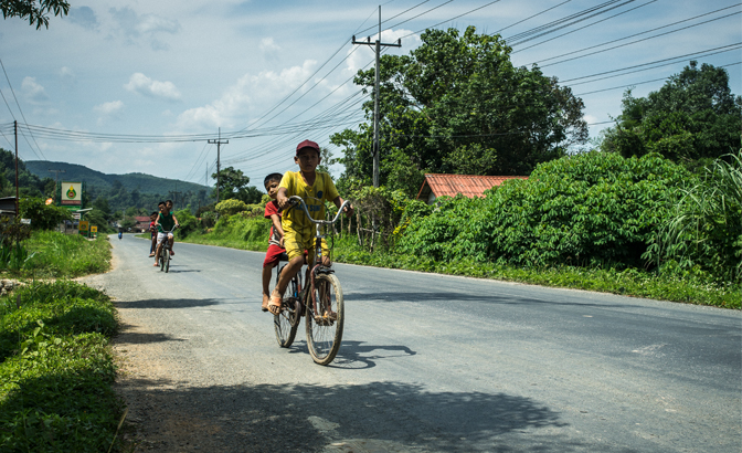 Children cycle home on the road to Luang Prabang