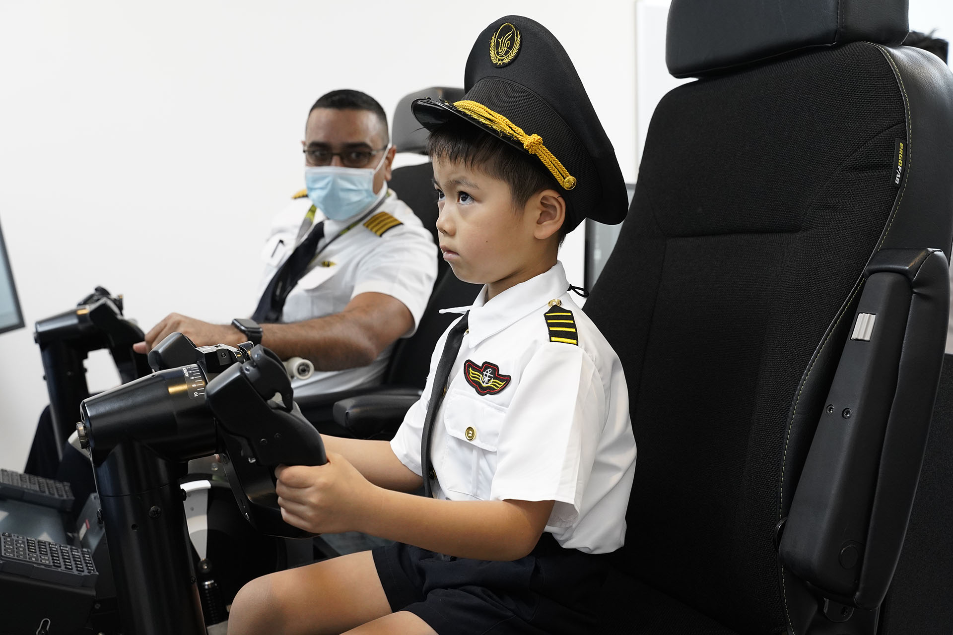 A junior pilot is being guided by an actual SIA pilot on the simulator