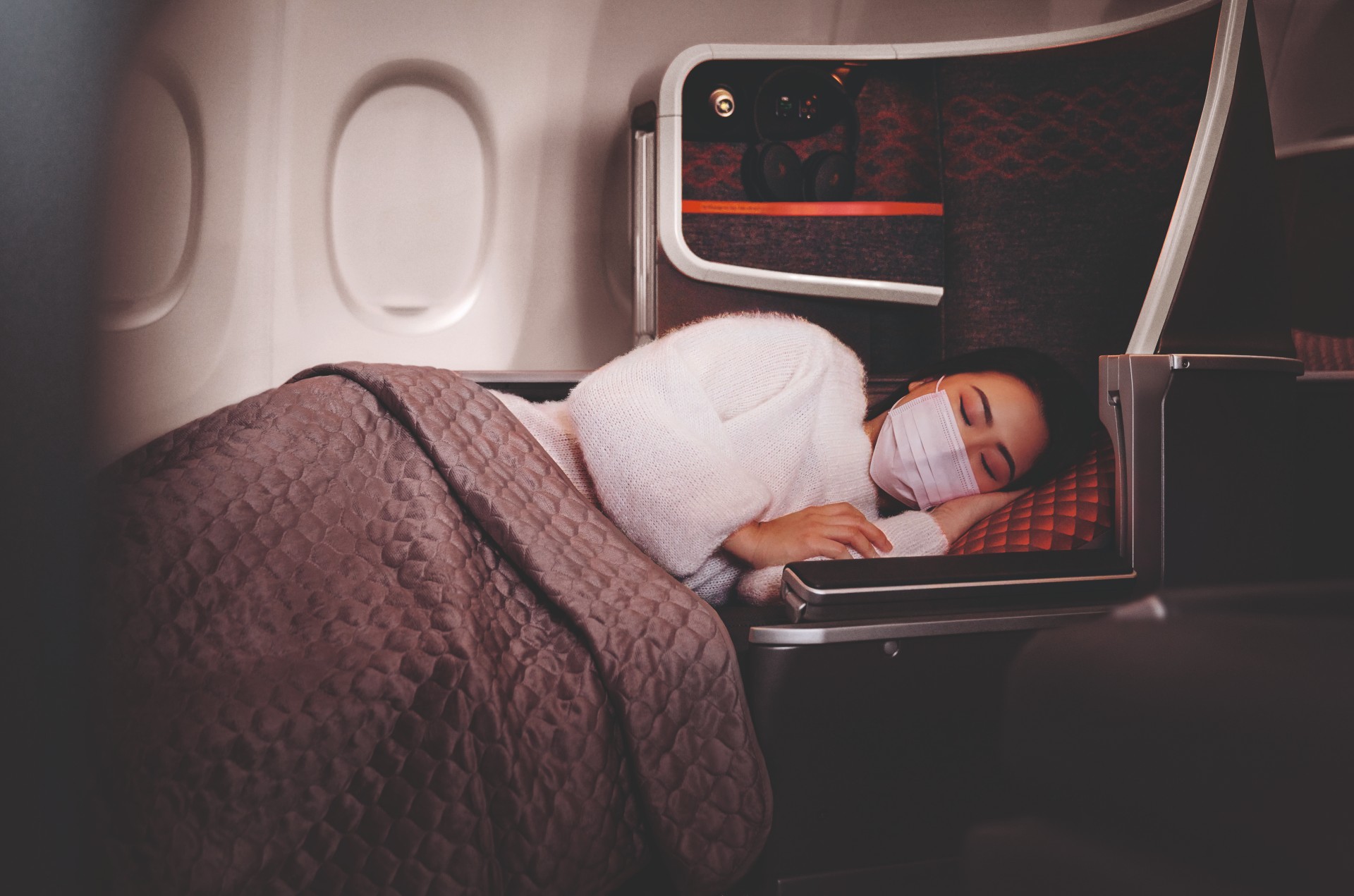 asian woman with mask sleeping in business class