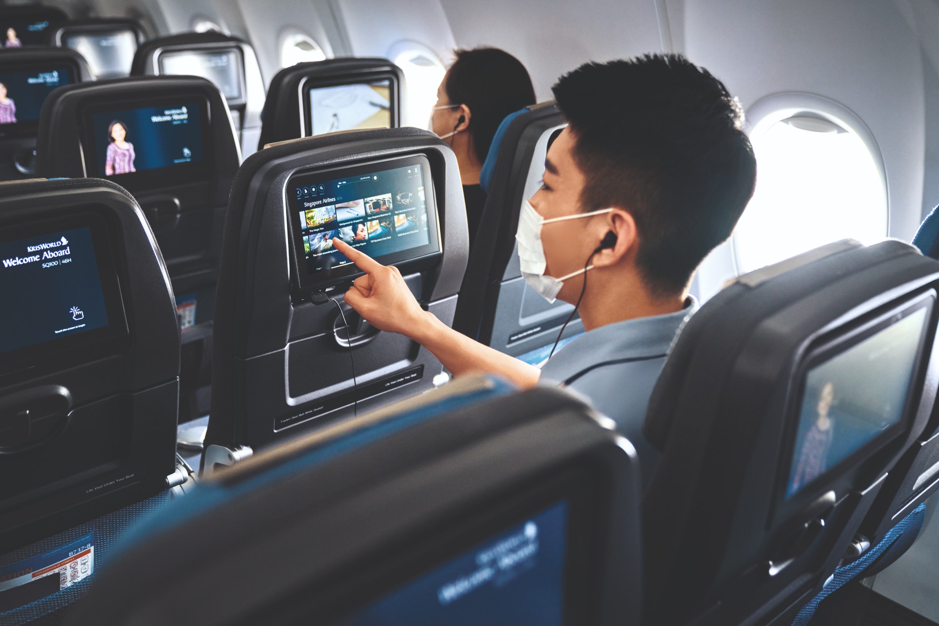 Asian man watching TV on Singapore Airlines